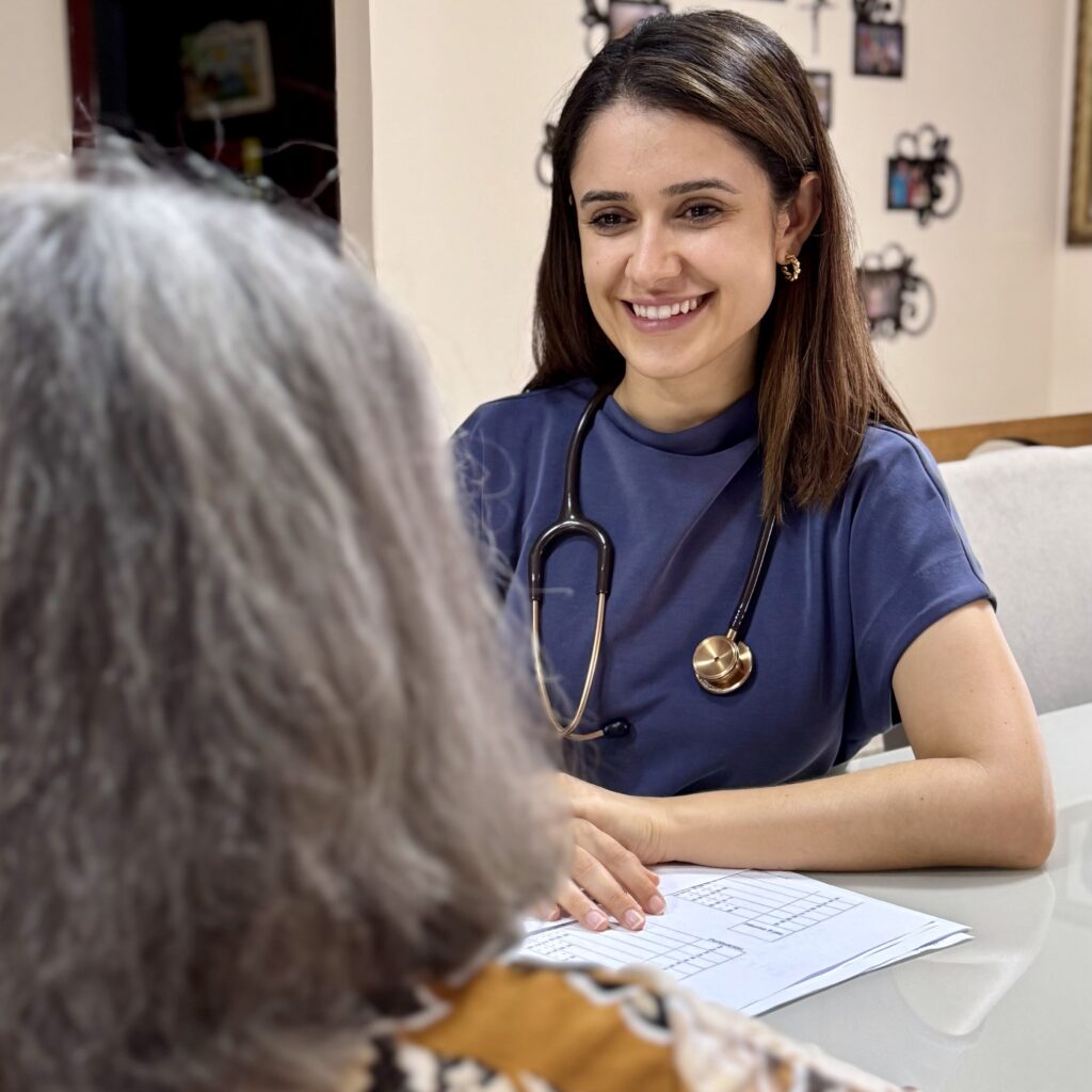 Uma médica sorridente conversa com uma paciente em um ambiente acolhedor.